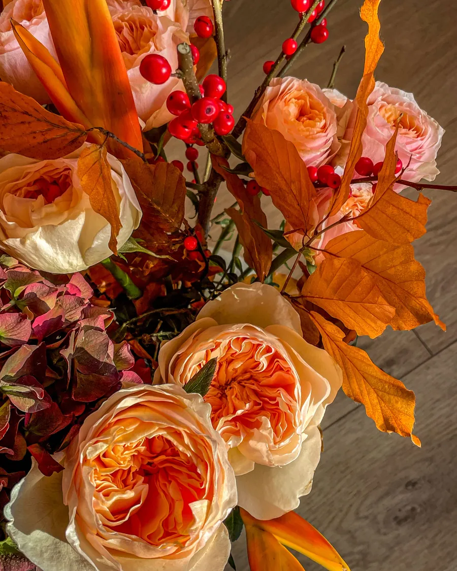 Orange roses, autumn leaves and red berries