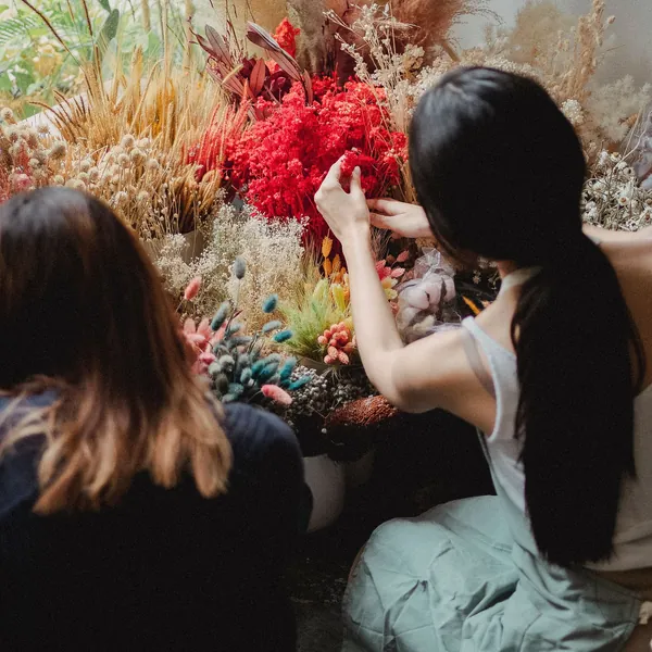 Florists arranging dried and fresh flowers at a workbench