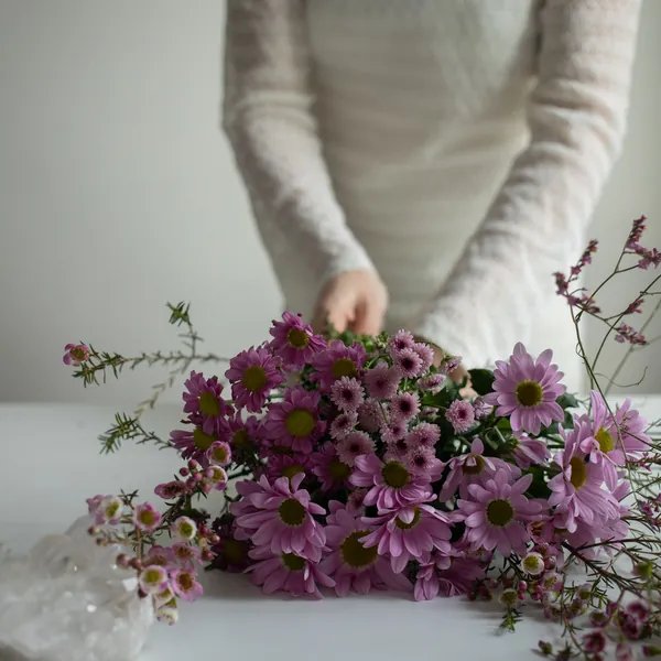 Hands arranging purple chrysanthemums