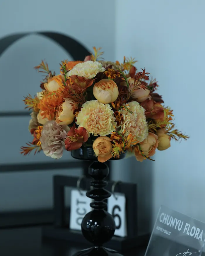 Autumn arrangement of roses and berries in a tall black vase