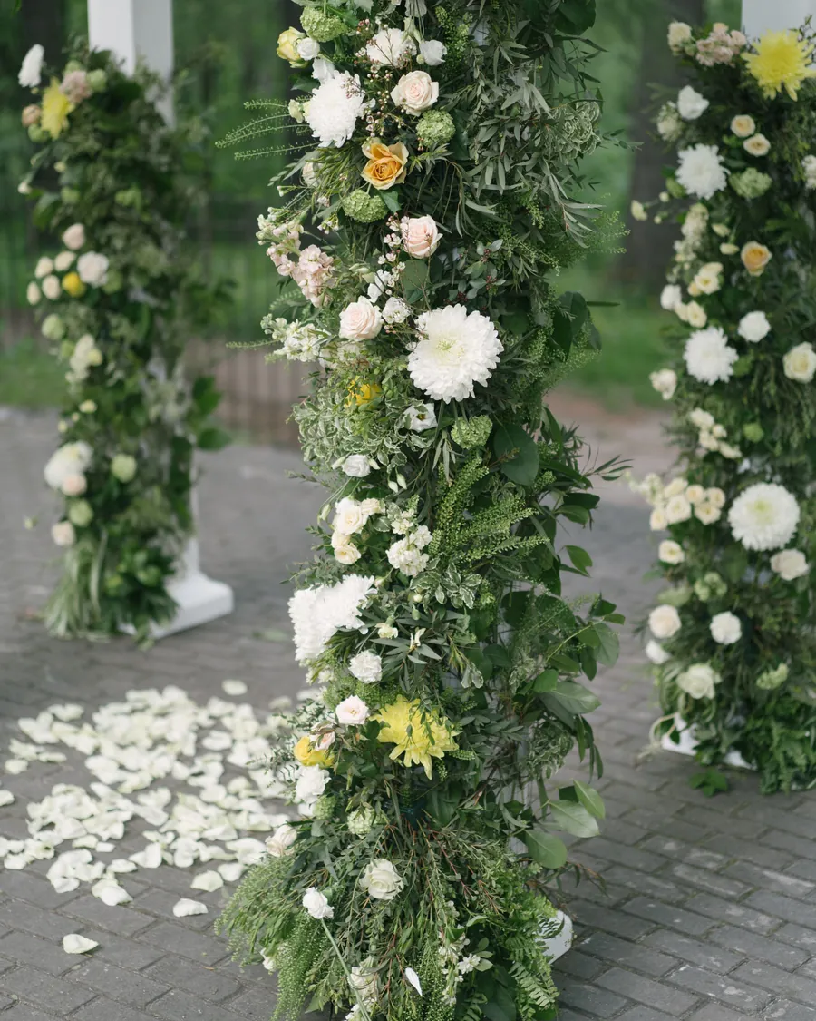 Ceremony pillars covered in white roses and greenery