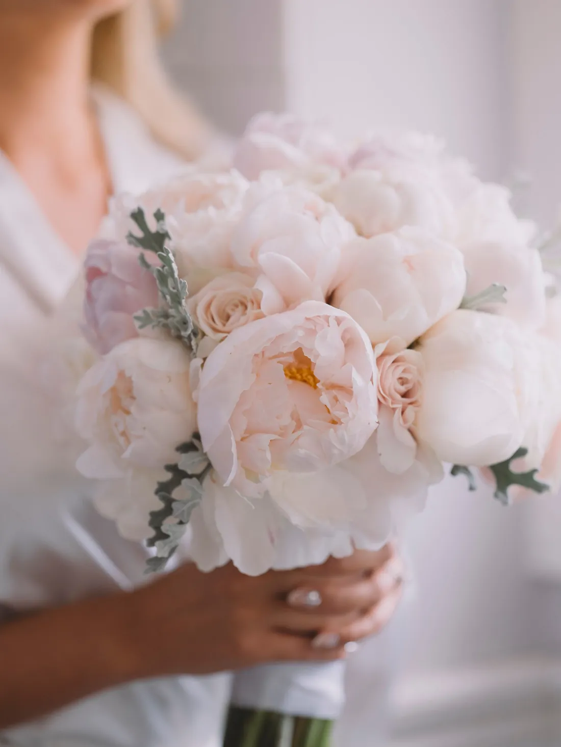 Bride holding a bouquet of blush peonies and white roses